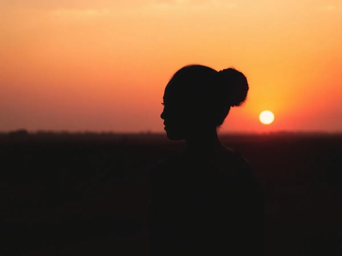 A woman’s silhouette against an orange sunset